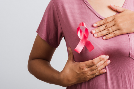 fotografia di una donna che segnala il suo seno a cui è appuntato un fiocco rosa